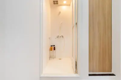 a white bathroom with a shower with a mirror at Fuufu House Tokyo SHIBUYA - No Elevator 4F WalkUp in Tokyo