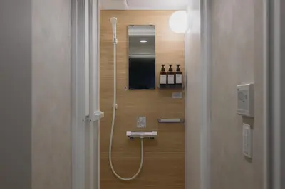 a walk in shower in a bathroom with a mirror at The Gallery Stay Monnaka in Tokyo