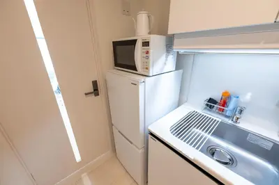 a small kitchen with a microwave on top of a refrigerator at LIVCITY Kinshicho 702 in Tokyo