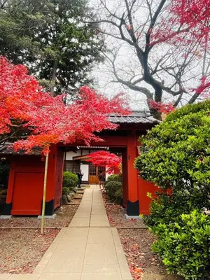 a red building with red trees and a sidewalk at Tokyo Maneki Stay Gotokuji in Tokyo