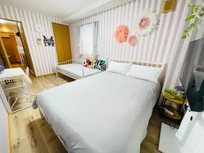 a bedroom with a white bed and a striped wall at Shitamachi Shin-Koiwa 201 in Tokyo