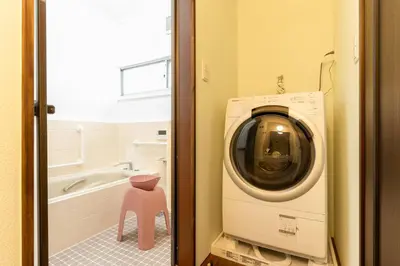 a washing machine in a bathroom with a pink stool at \u548c\u6c23\u4f1a\u3005\u5357\u9577\u5d0e Wakiaiai Minaminagasaki in Tokyo