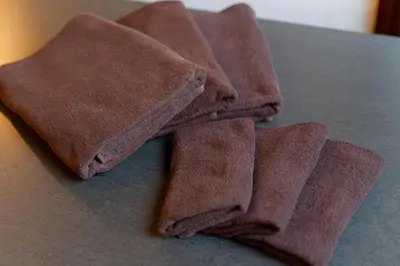 a pile of brown towels sitting on a table at \u548c\u6c23\u4f1a\u3005\u5357\u9577\u5d0e Wakiaiai Minaminagasaki in Tokyo