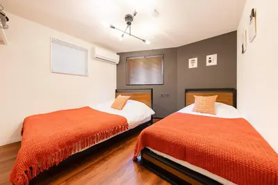 a bedroom with two beds with orange sheets at tai\u5357\u5143\u753a25 in Tokyo