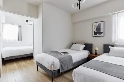 two beds in a room with white walls and wood floors at Azabu artemis in Tokyo