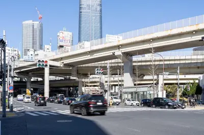 a busy city street with cars driving under an overpass at Azabu artemis in Tokyo
