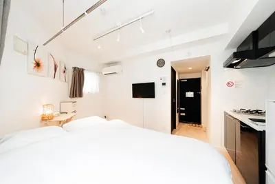 a white bedroom with a bed and a kitchen at NDZ101 3 min walk to station, 2 lines, Yamanote Line, high-speed Wi-Fi in Tokyo