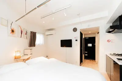 a white bedroom with a bed and a kitchen at NDZ101 3 min walk to station, 2 lines, Yamanote Line, high-speed Wi-Fi in Tokyo