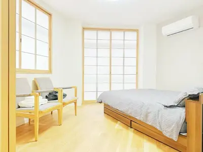 a bedroom with a bed and a chair and windows at \u6587\u4eachouse 201\u5ba4 in Tokyo