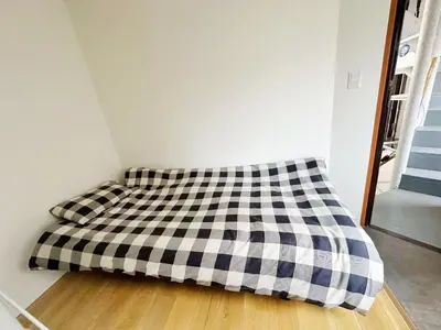 a bed in a room with a checkered blanket at \u6587\u4eachouse 201\u5ba4 in Tokyo