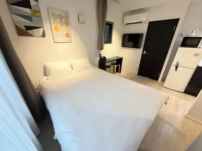 a large white bed in a room with a refrigerator at NDZ103 3 min walk to station, 2 lines, Yamanote Line, high-speed Wi-Fi in Tokyo
