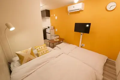 a bedroom with a bed and a clock on the wall at TOMALCO INN NAKANO 1 4F Flat 2 Bath 13min to Shinjuku from Honancho in Tokyo