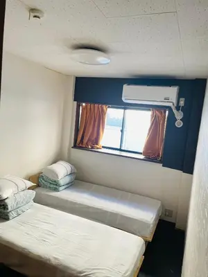 a small room with two beds and a window at Lucky Hostel in Tokyo