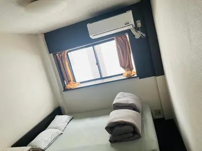a small room with two beds and a window at Lucky Hostel in Tokyo