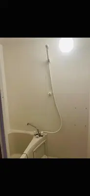a bathroom with a toilet with a light on the wall at Lucky Hostel in Tokyo