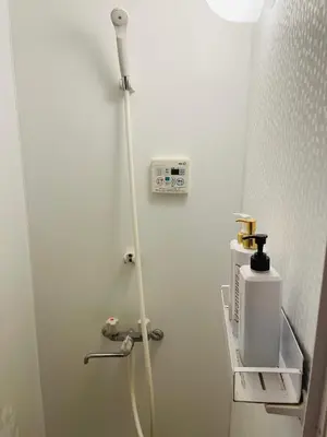 a small bathroom with a shower with a white wall at Lucky Hostel in Tokyo