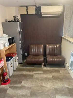 a room with two leather chairs and a refrigerator at Lucky Hostel in Tokyo
