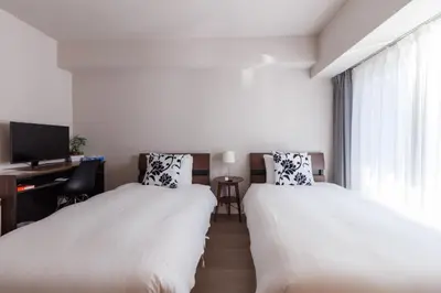 two beds in a room with a desk and a tv at LANG HOTEL Kameido - Vacation STAY 79534v in Tokyo