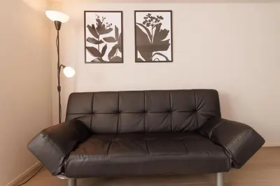 a leather couch in a living room with three pictures on the wall at LANG HOTEL Kameido - Vacation STAY 79042v in Tokyo