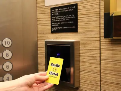 a person holding a smile hotel sign in front of a box at Smile Hotel Shinagawa Sengakuji Ekimae - Vacation STAY 67645v in Tokyo