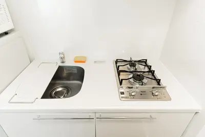 a white kitchen with a stove and a sink at NDZ203 3 min walk to station, 2 lines, Yamanote Line, high-speed Wi-Fi in Tokyo