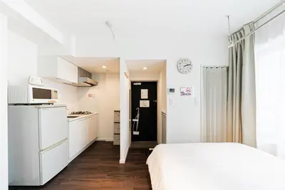 a white bedroom with a bed and a kitchen at NDZ203 3 min walk to station, 2 lines, Yamanote Line, high-speed Wi-Fi in Tokyo