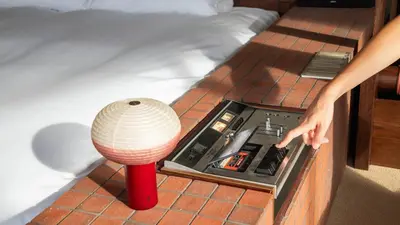 a person reaching for a lamp on a bed at SOIL Nihonbashi Hotel in Tokyo