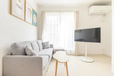 a white living room with a couch and a tv at Near Shinjuku 3 stops in Tokyo