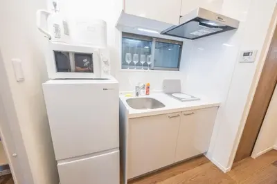 a small kitchen with a refrigerator and a sink at Hiro Yanaka hotel TT0421 in Tokyo