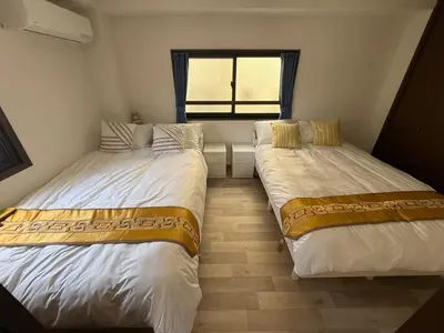 two beds in a small room with a window at \u671d\u65e5\u8857\u306e\u5bbf An inn on Asahi Street in Tokyo