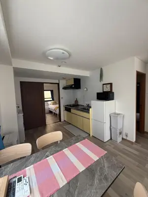 a kitchen and living room with a table and a refrigerator at \u671d\u65e5\u8857\u306e\u5bbf An inn on Asahi Street in Tokyo