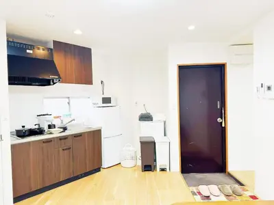 a white kitchen with a black door and wooden cabinets at \u6587\u4eachouse 202 in Tokyo