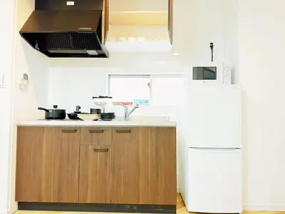 a kitchen with wooden cabinets and a white refrigerator at \u6587\u4eachouse 202 in Tokyo