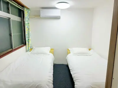 two beds in a room with white sheets at \u6587\u4eachouse103 in Tokyo