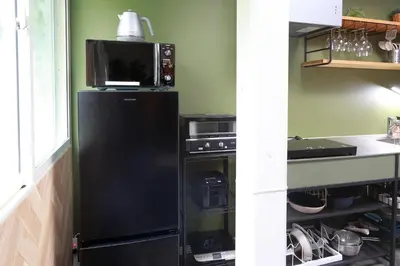 a black refrigerator in a kitchen with a microwave at Oneness House Tokyo \u6771\u4eac\u56db\u30c4\u6728 in Tokyo