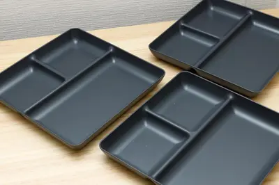 three black plastic trays sitting on a wooden table at M-Stay Nishishinjuku II, Room 202 in Tokyo