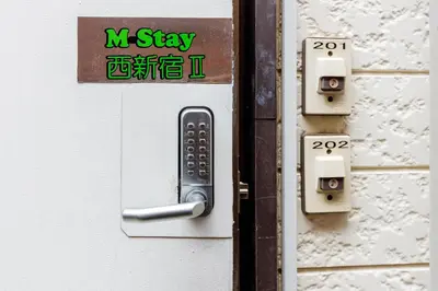 a remote control sticking out of a door at M-Stay Nishishinjuku II, Room 202 in Tokyo