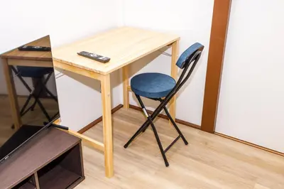 a desk with a blue chair next to a table at M-Stay Nishishinjuku II, Room 202 in Tokyo