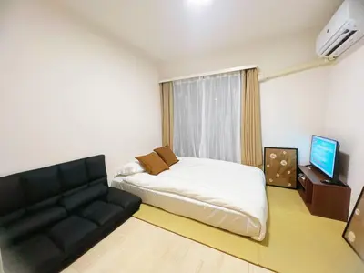 a bedroom with a bed and a couch and a television at \u4ea4\u901a\u4fbf\u5229 \u6c60\u888b\u5468\u8fba \u685c\u306e\u901a1-3\u4eba\u6c60\u888b4\u5206 \u65b0\u5bbf10\u5206 \u6e0b\u8c3714\u5206 \u76f4\u901a in Tokyo