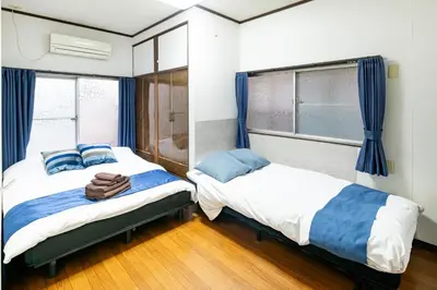two beds in a bedroom with blue curtains at Nakaitabashi Kotate - Vacation STAY 19730 in Tokyo