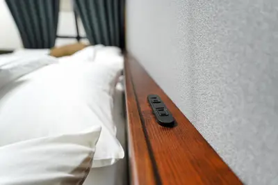 a remote control sitting on the edge of a bed at \u30e1\u30fc\u30a4\u30f3\u65b0\u5bbf in Tokyo