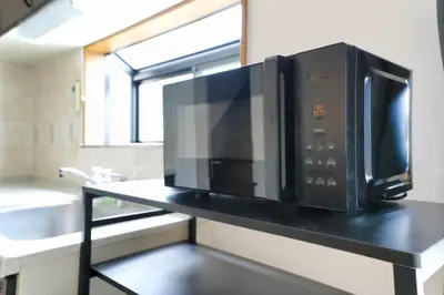 a microwave on a black counter in a kitchen at \u30e1\u30fc\u30a4\u30f3\u65b0\u5bbf in Tokyo