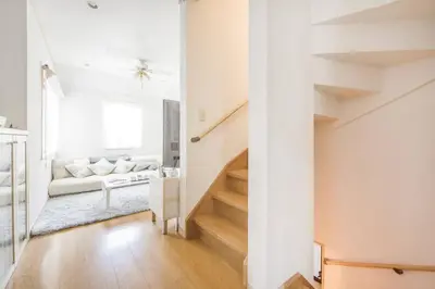 a white living room with a couch and stairs at Yoyogi Detached house Y4BD in Tokyo