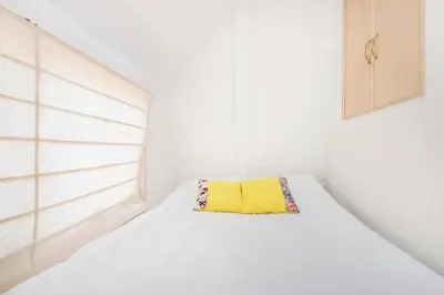 a white bedroom with a yellow pillow on a bed at Yoyogi Detached house Y4BD in Tokyo