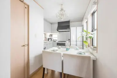a kitchen with white cabinets and a kitchen island with two chairs at Yoyogi Detached house Y4BD in Tokyo