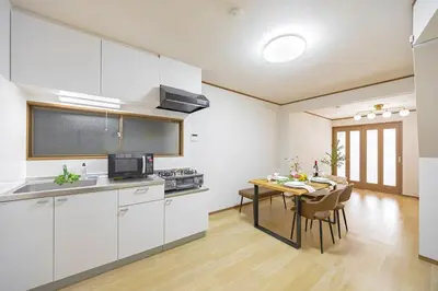 a kitchen with white cabinets and a dining table at Bnn\u5800\u52072\u4e01\u76eeESTA III in Tokyo