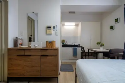 a bedroom with a bed and a kitchen with a table at CraftFlat Komagome 602, a compact studio at excellent location in Tokyo