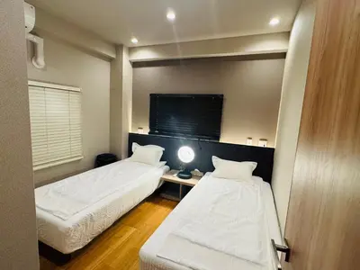 a room with two beds and a table with a lamp at AhaiHotel in Wada