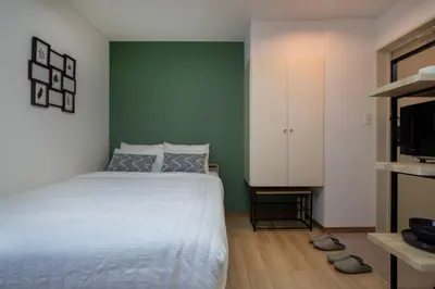 a bedroom with a white bed and a green wall at CraftFlat Komagome 601, a compact studio at excellent location in Tokyo