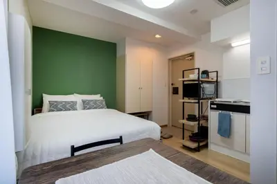 a bedroom with a white bed and a green wall at CraftFlat Komagome 601, a compact studio at excellent location in Tokyo